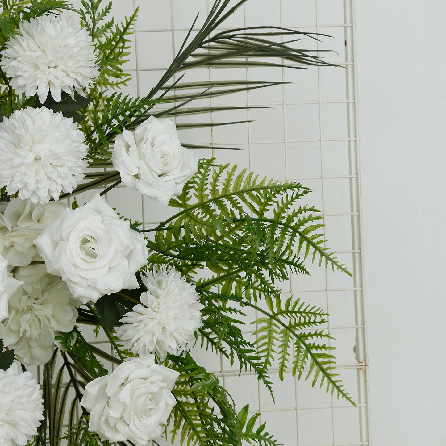 Ivory rose and chrysanthemum floral arrangement with greenery and palm leaves.