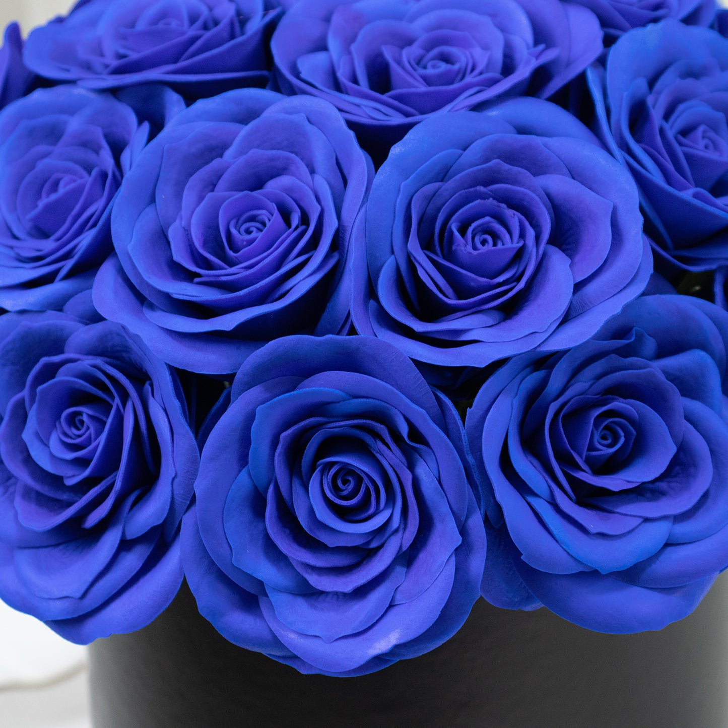 Royal blue rose centerpiece arrangement in a black round gift box.