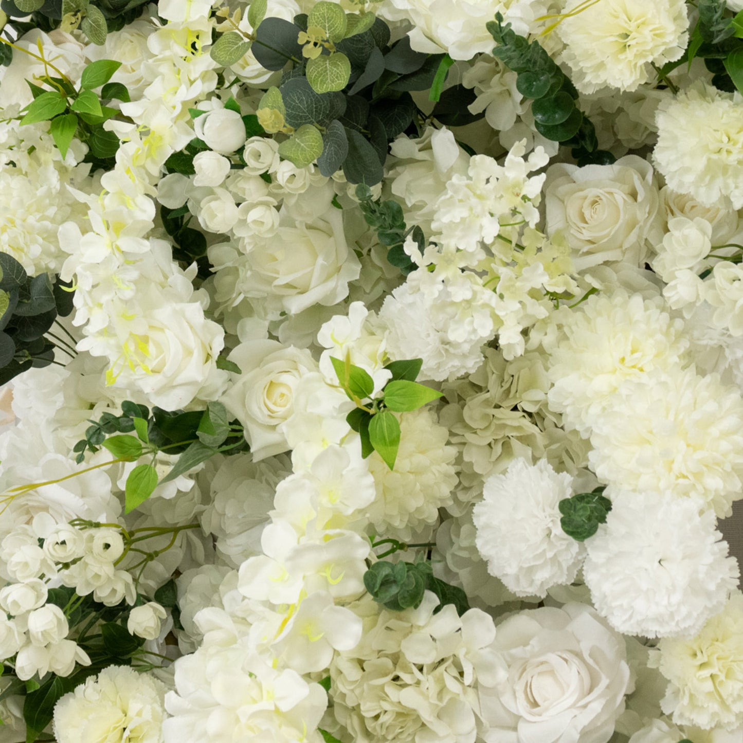 White floral backdrop with artificial roses, hydrangeas, and chrysanthemums.