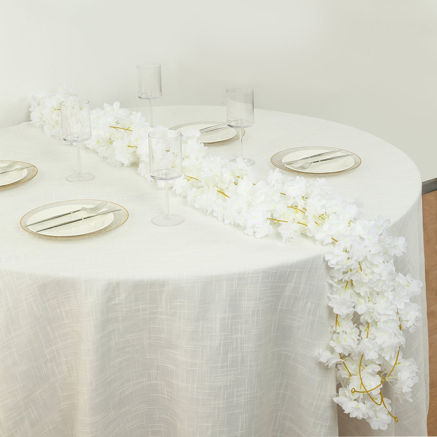 White artificial cherry blossom floral garland on a table setting.