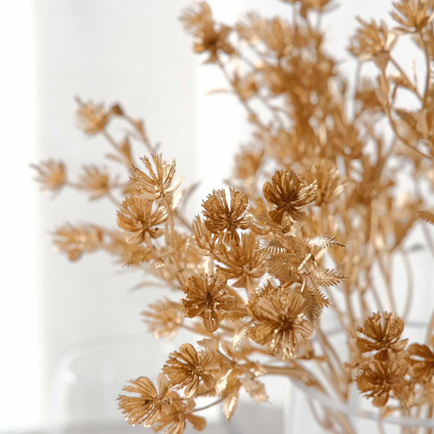 Metallic gold artificial baby's breath flower bushes in a decorative arrangement.