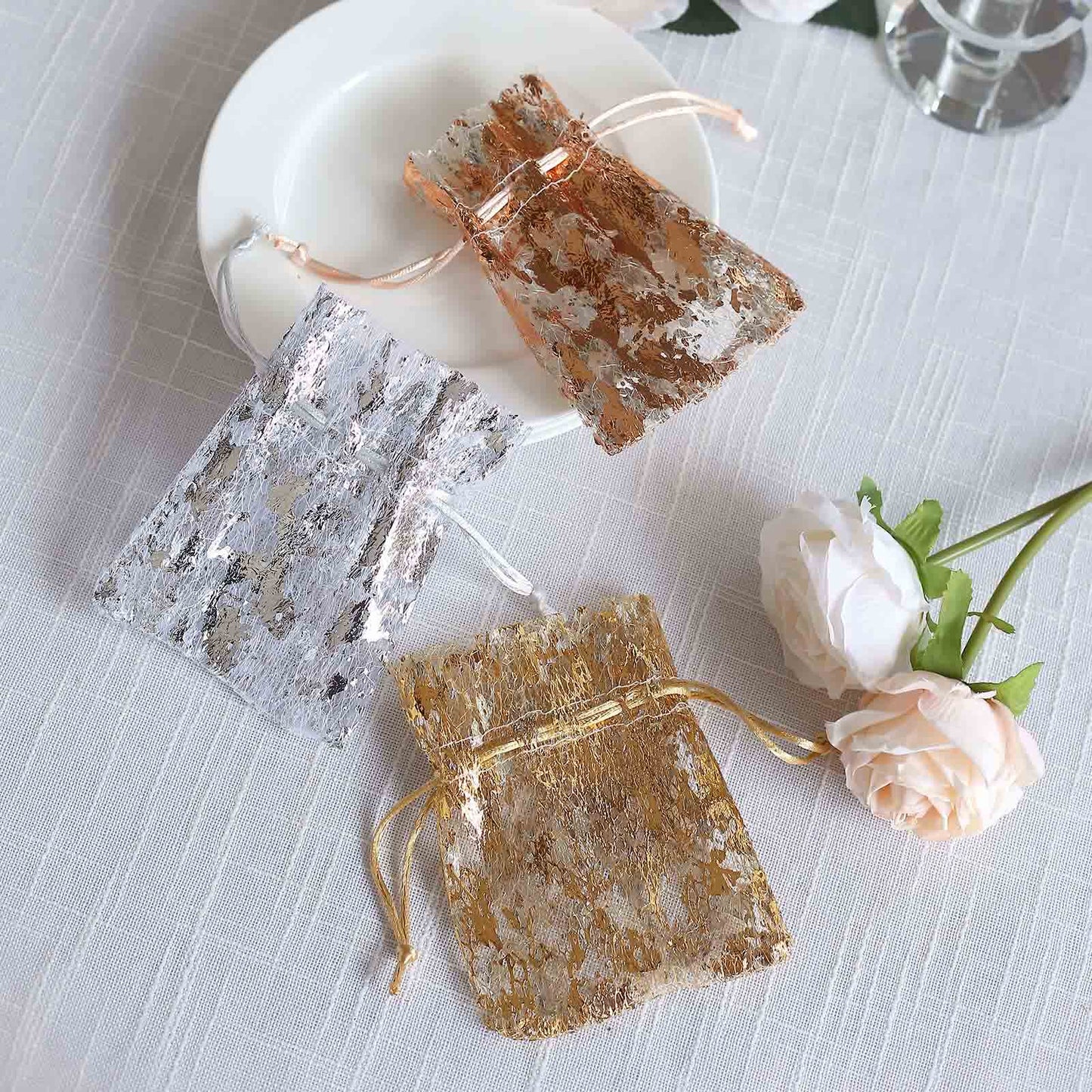 Metallic rose gold and silver drawstring candy bags on a plate.