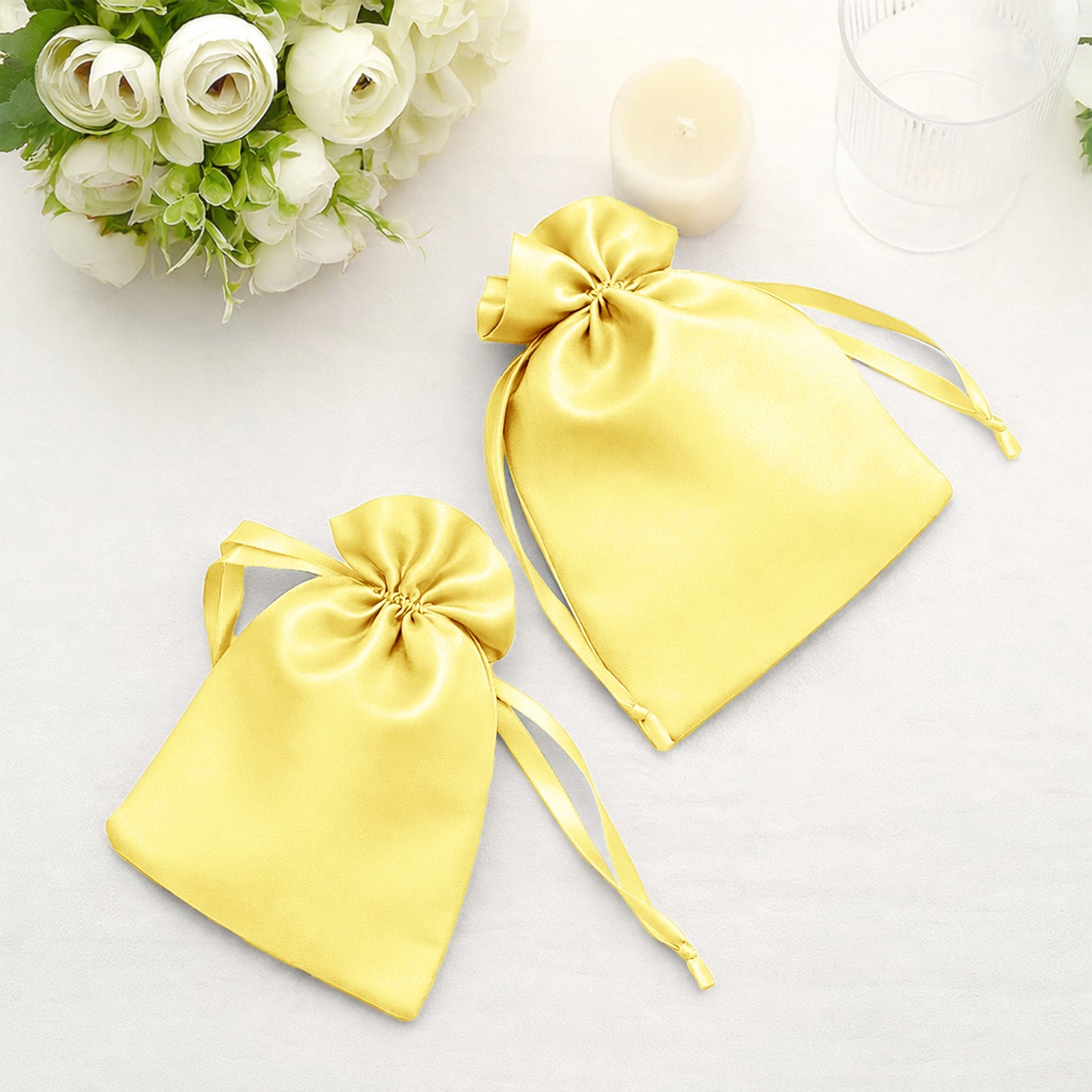 Yellow satin drawstring wedding favor gift bags on a table.