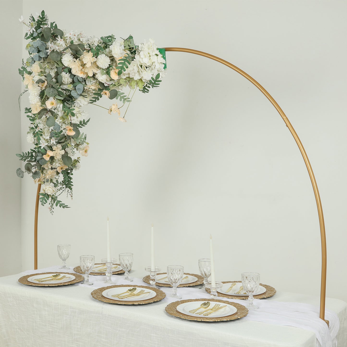 Heavy duty gold metal wedding arch with floral decor and elegant table setting.