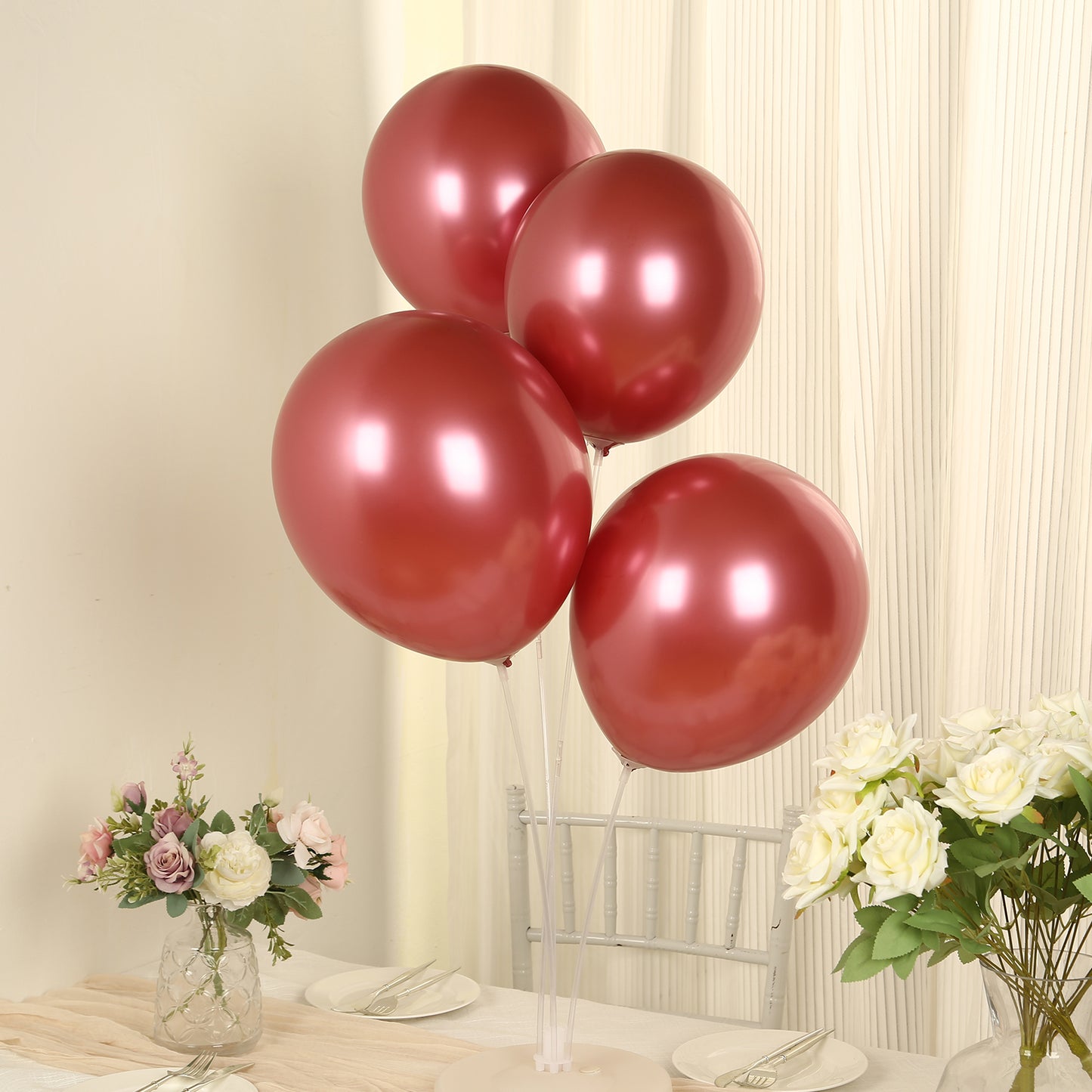 Red metallic balloons on a table setting with flowers.