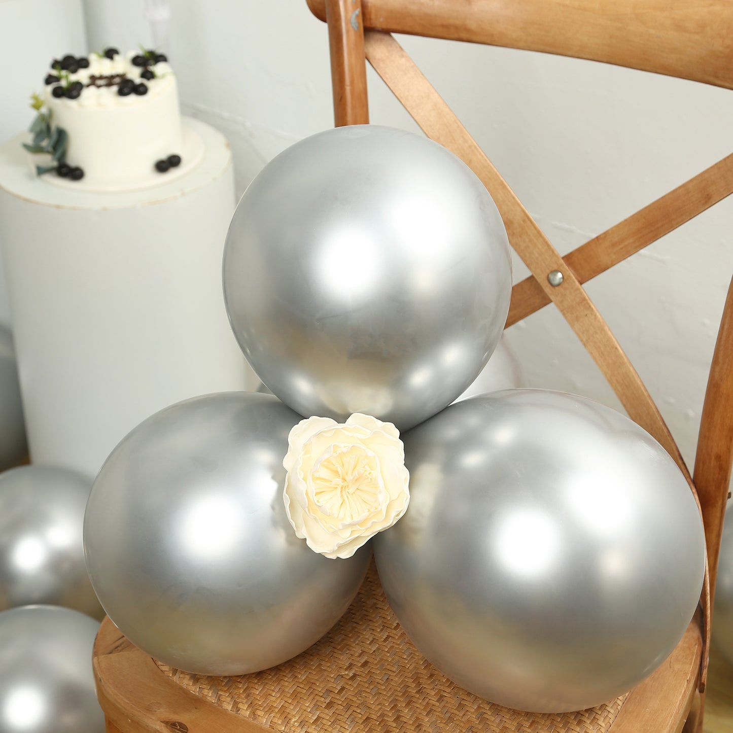 Chrome silver biodegradable latex balloons stacked on a chair.
