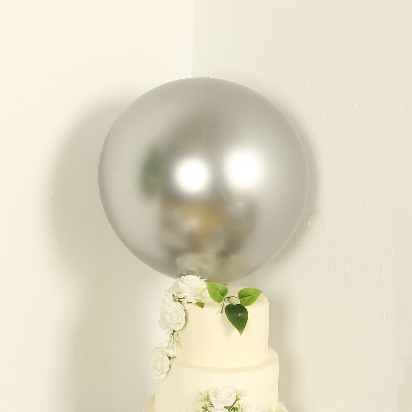 Metallic chrome silver biodegradable balloon on a cake with flowers.