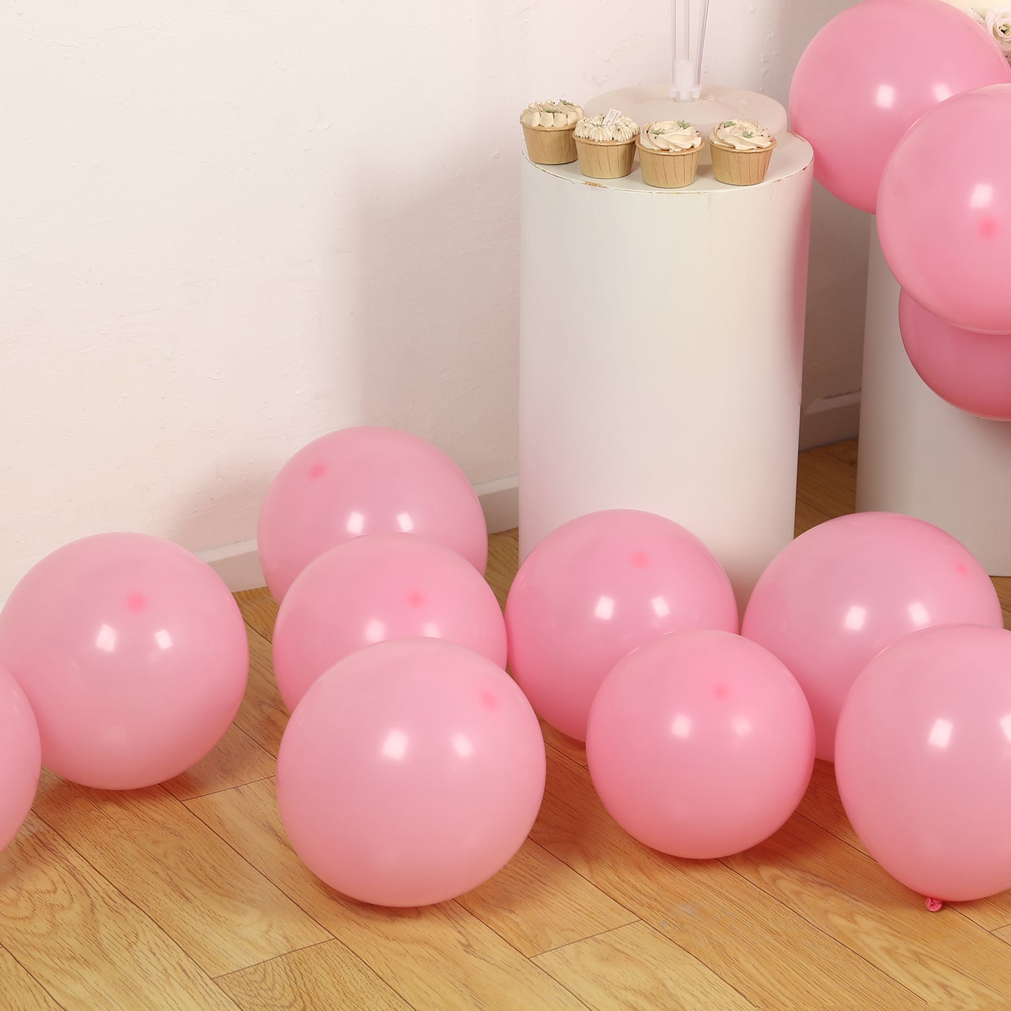Matte pastel pink biodegradable balloons on a wooden floor.