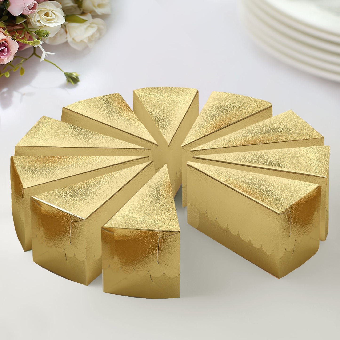 Metallic gold triangular cake boxes arranged in a circle on a table.
