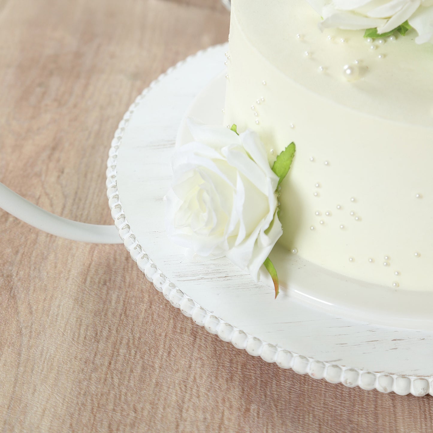 Whitewash metal floral hoop cake stand with beaded wooden base.