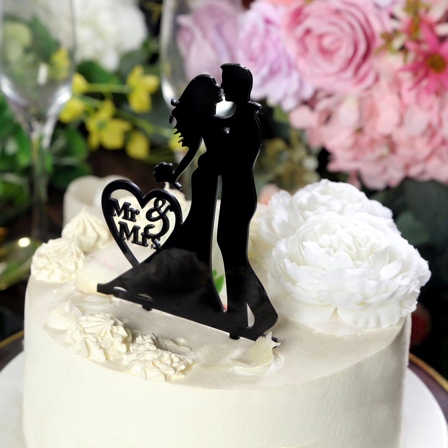 Black wedding cake topper featuring a silhouette of a bride and groom.