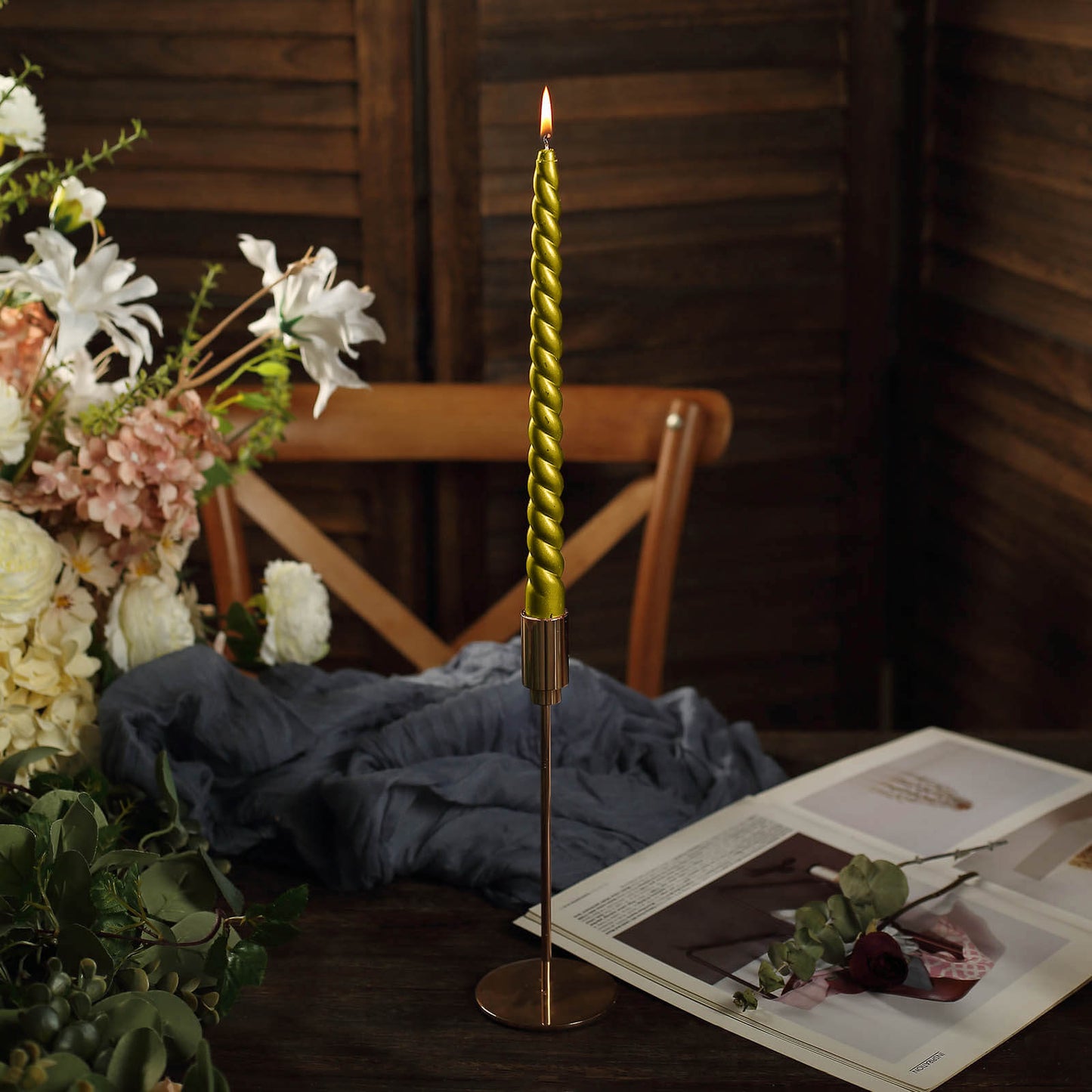 Gold spiral taper candle in a decorative holder on a styled table setting.