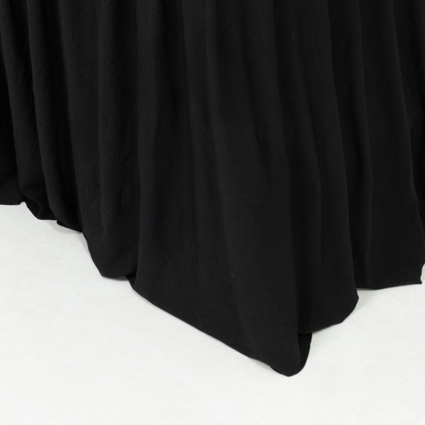 Black spandex pleated folding chair cover with floor-length skirt.