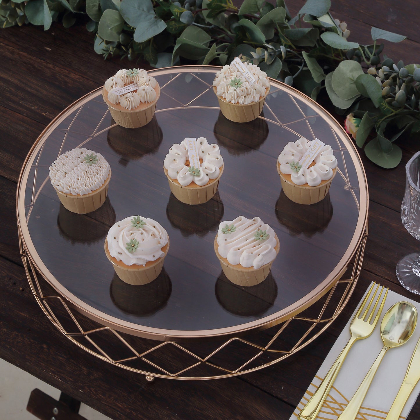 Gold metal geometric cake stand displaying decorated cupcakes.