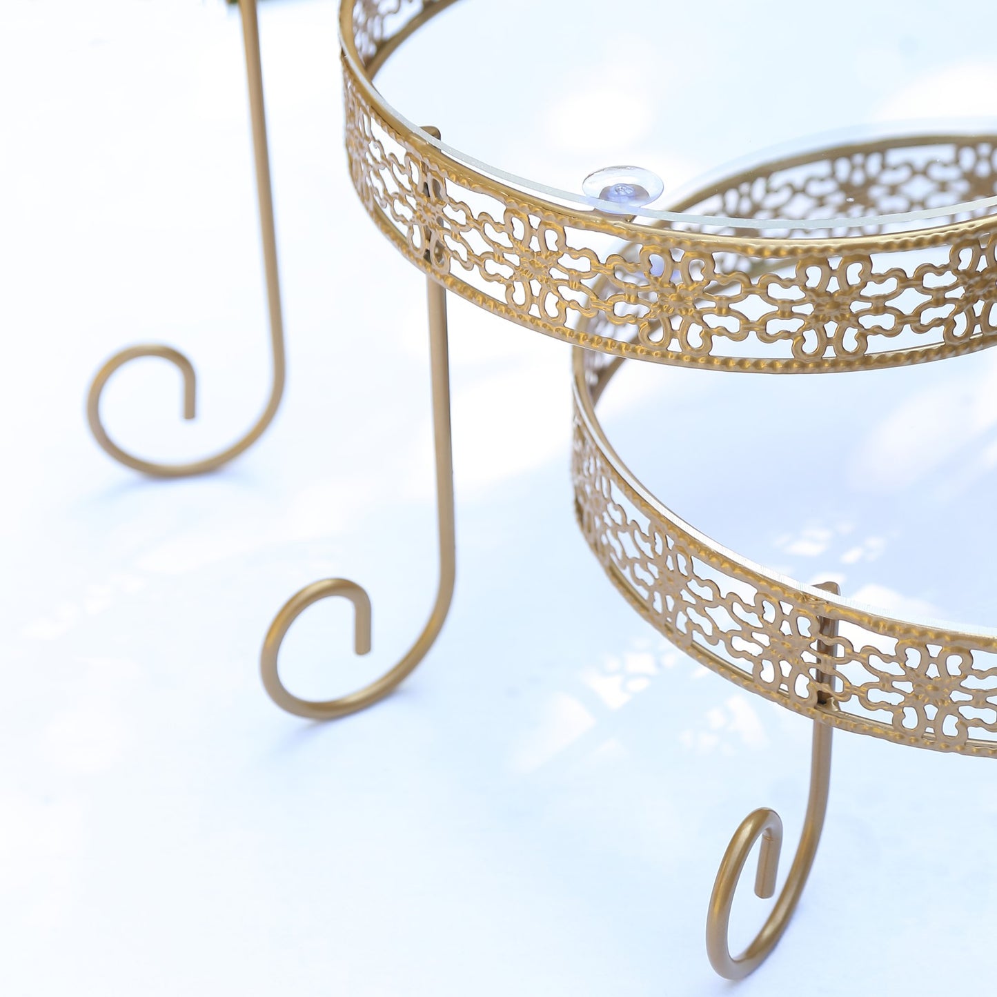 Gold metal rotating cake stand with clear acrylic plates and lace design.