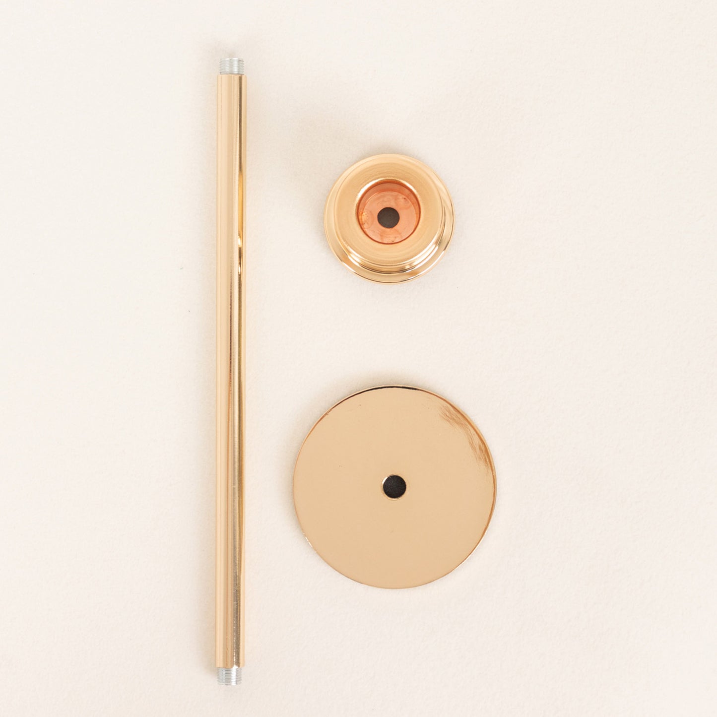Gold metal candlestick holder parts on a light background.