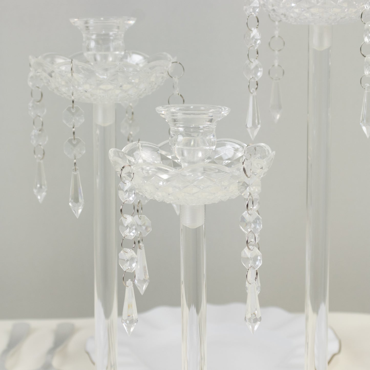 Set of 3 clear acrylic taper candle holders with hanging beads and prism accents.