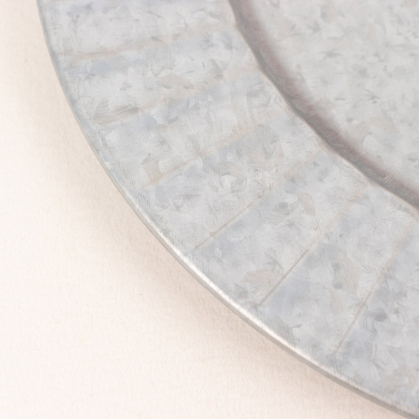 Silver galvanized metal charger plate with ruffled rim.