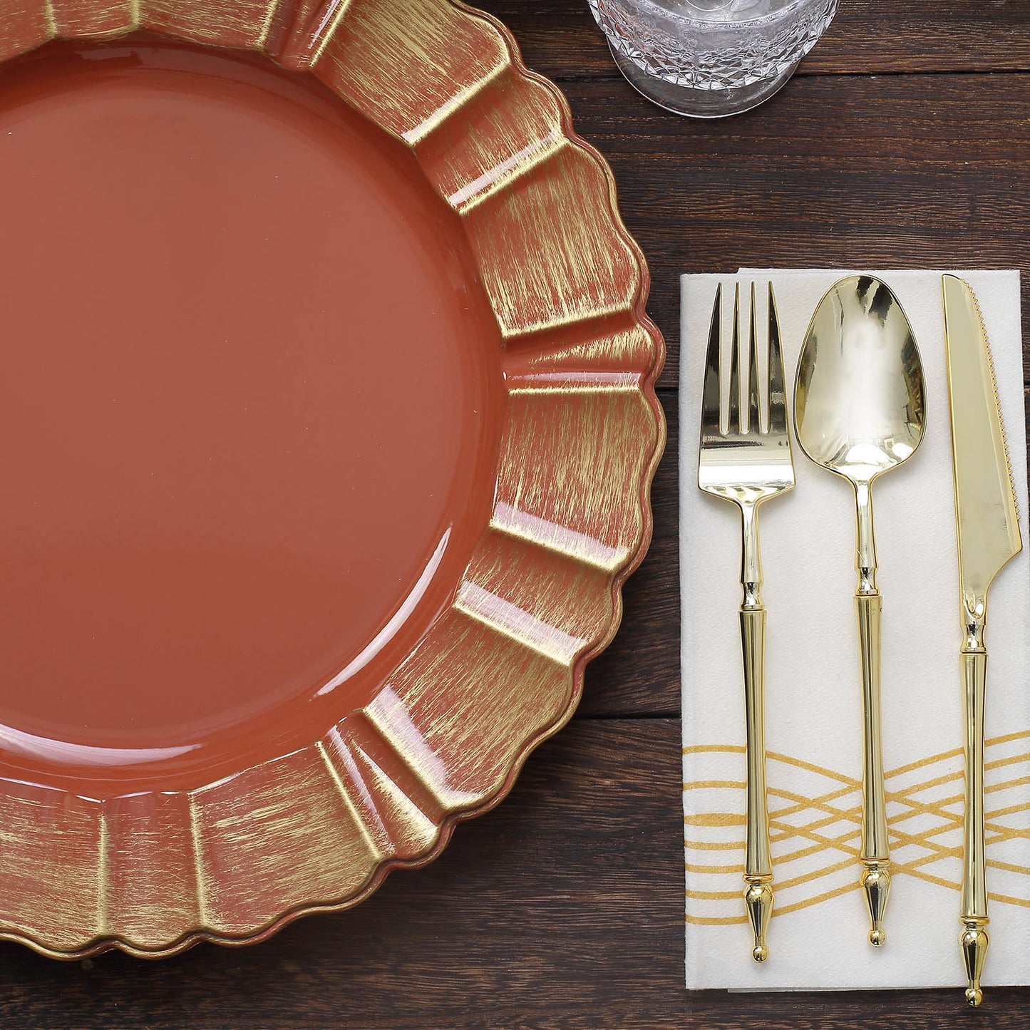 Rust terracotta charger plate with gold brushed wavy scalloped rim.