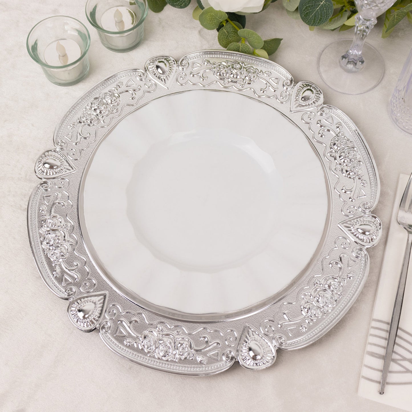 Silver round acrylic charger plate with floral embossed scalloped rim.