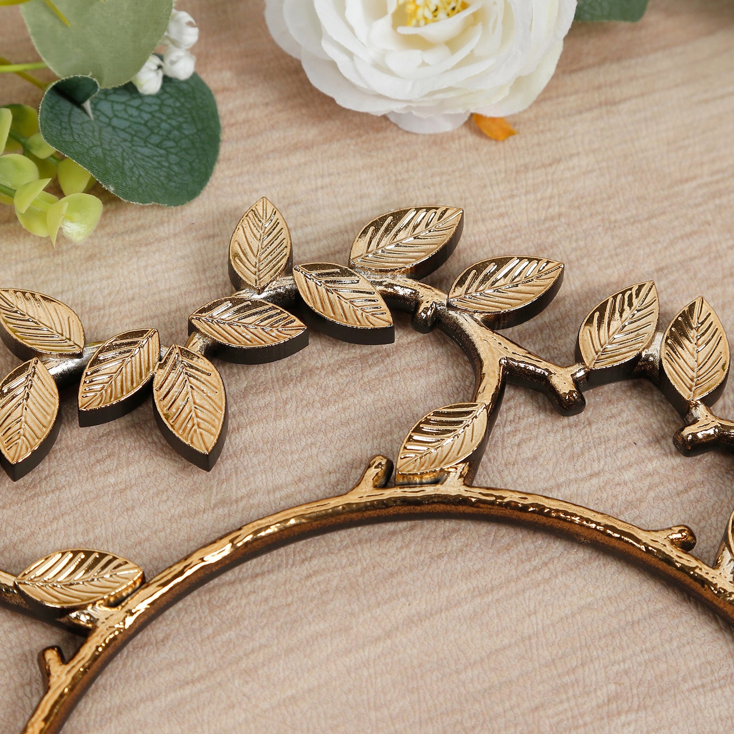 Gold leaf decorative charger plate with intricate wreath design.