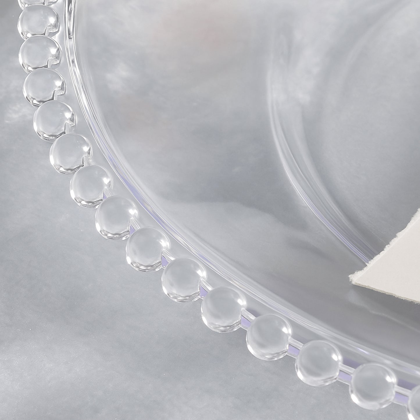 Clear acrylic charger plate with beaded rim.
