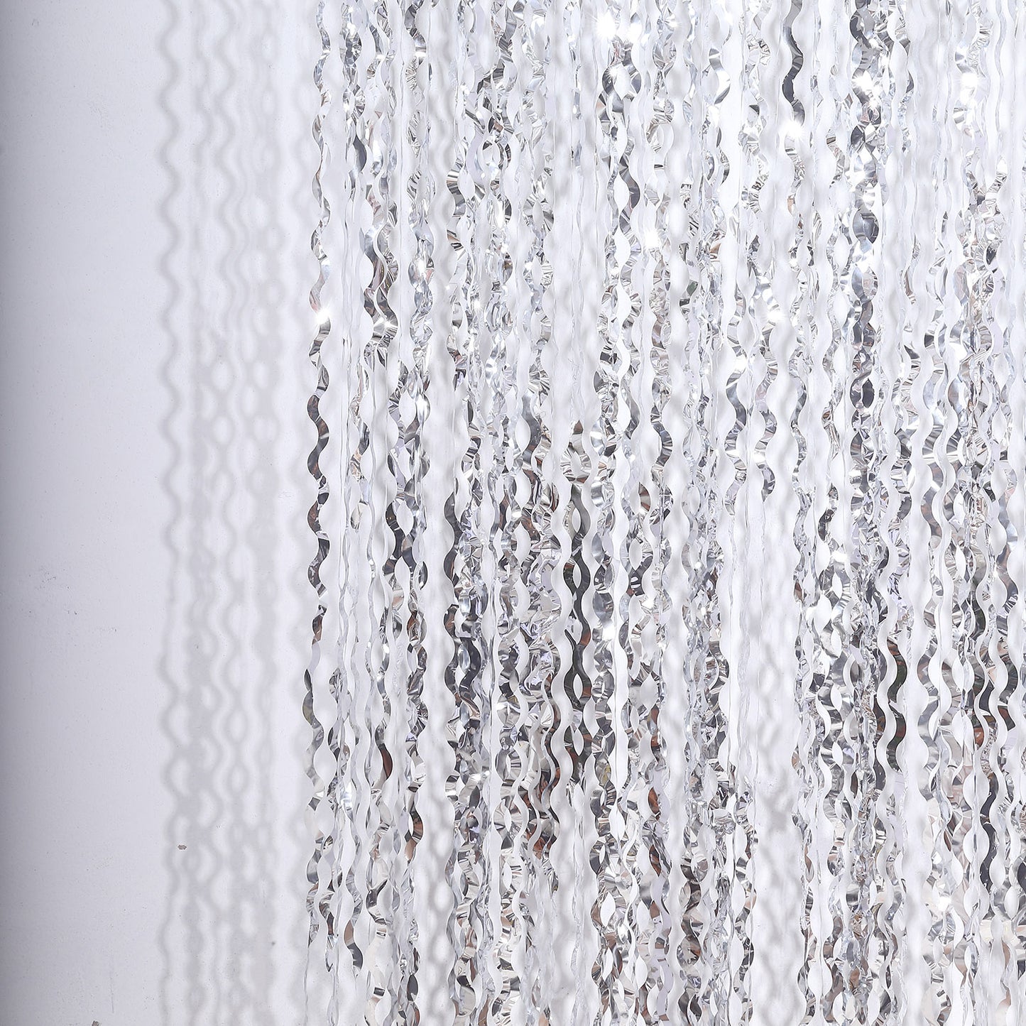 Metallic silver wavy foil fringe backdrop curtain for parties.