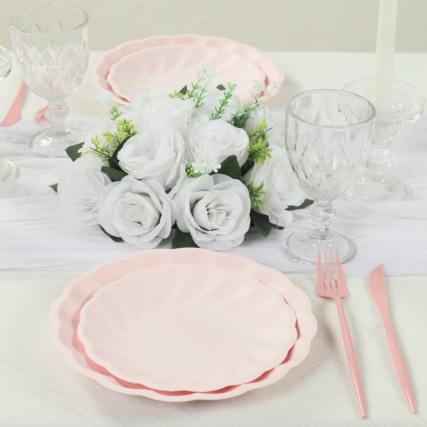 Blush biodegradable salad plates with scalloped edges on a table setting.