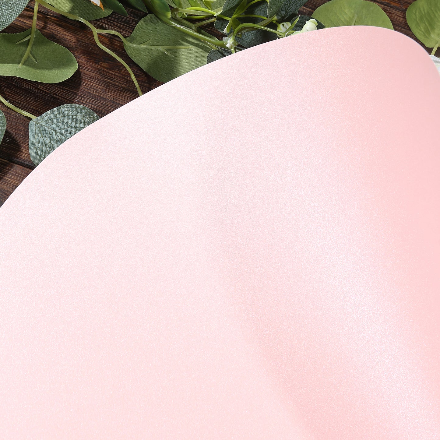 Pink disposable paper placemat with a smooth finish on a wooden surface.