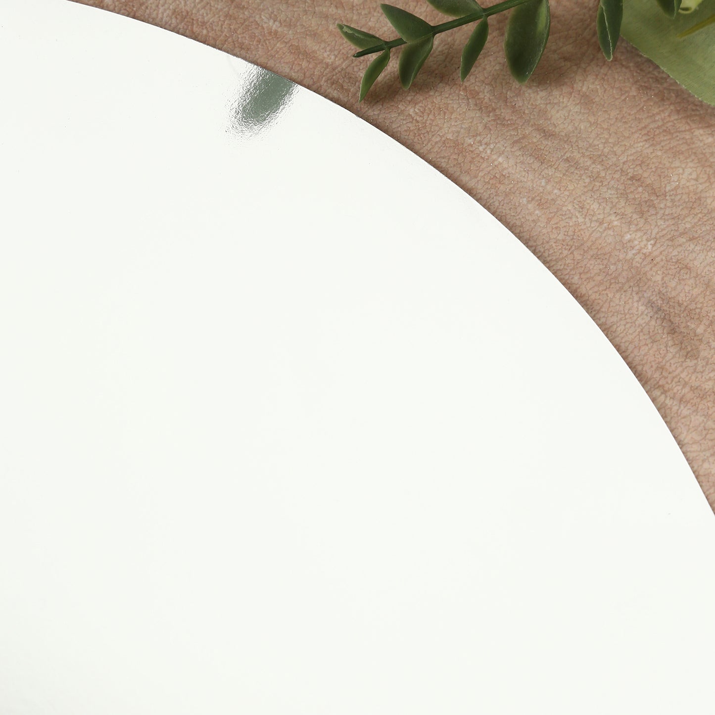 Silver round disposable table placemat on a wooden surface.