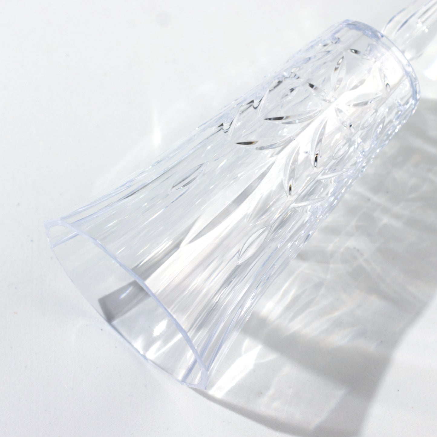 Clear reusable champagne flute with embossed leaf pattern.