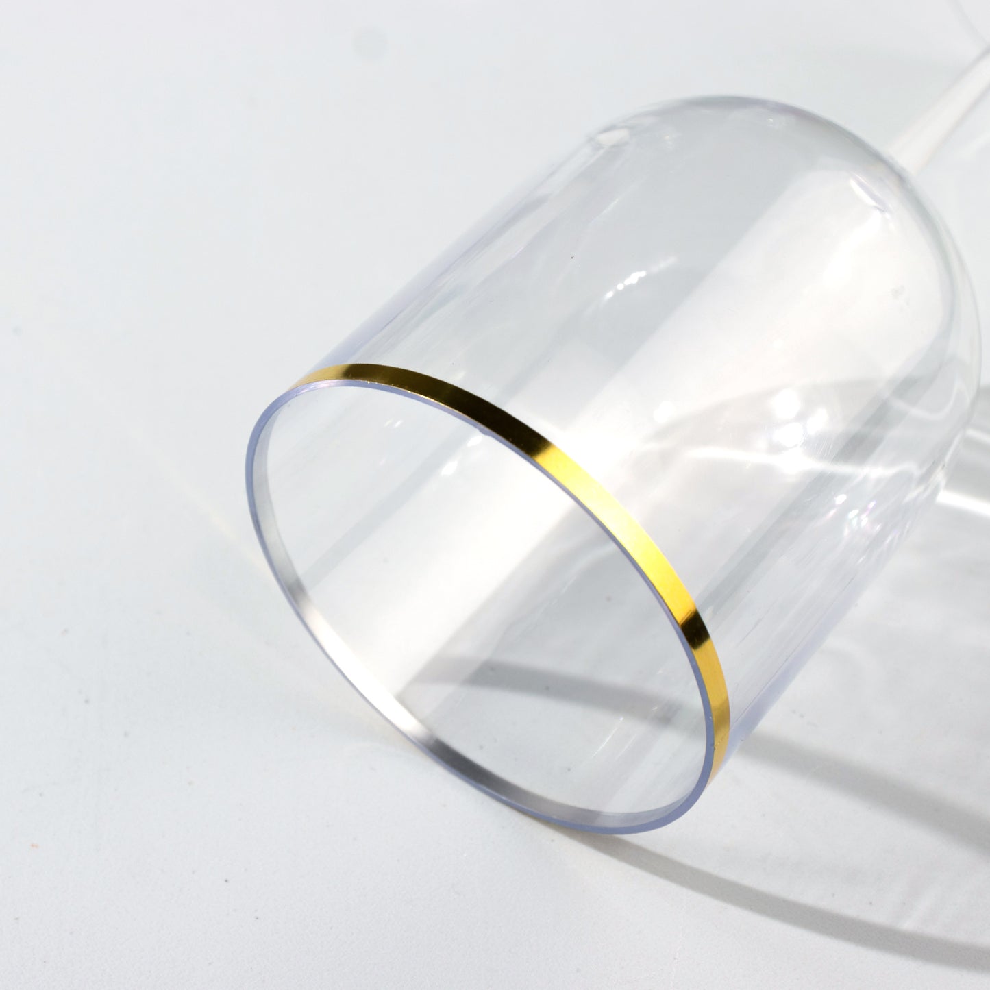Clear plastic wine goblet with gold rim, premium disposable glassware.