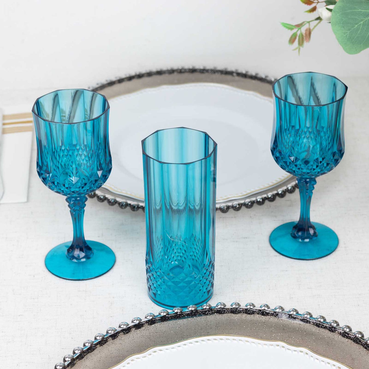 Ocean blue crystal cut reusable plastic cocktail goblets on a table.