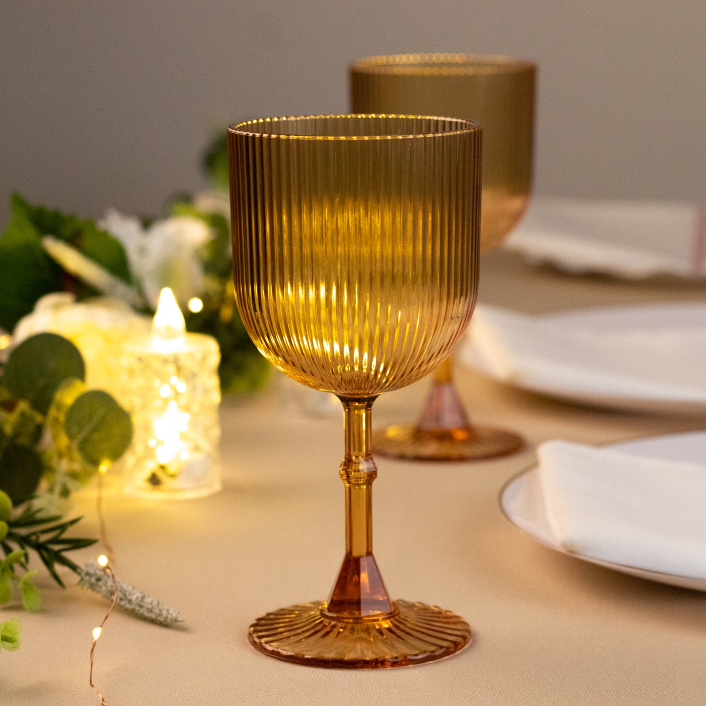 Amber gold ribbed reusable plastic wine goblets on a table.