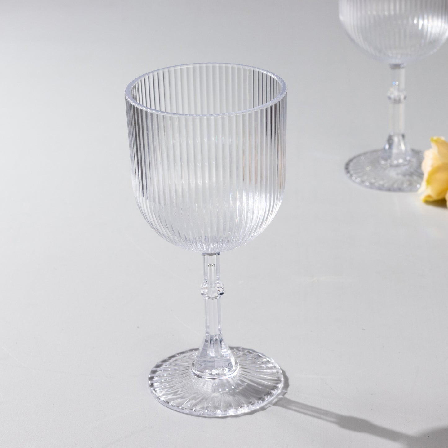Clear ribbed reusable plastic wine goblet, shatterproof vintage design.