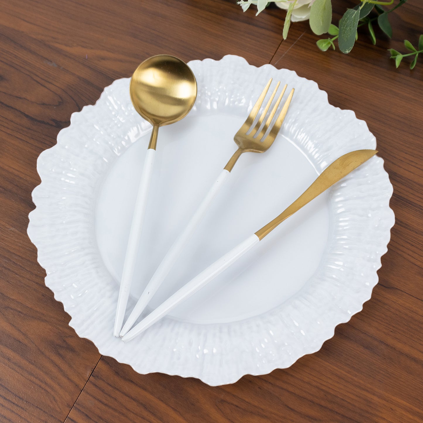 Pearl white plastic dinner plate with elegant reef design and gold utensils.
