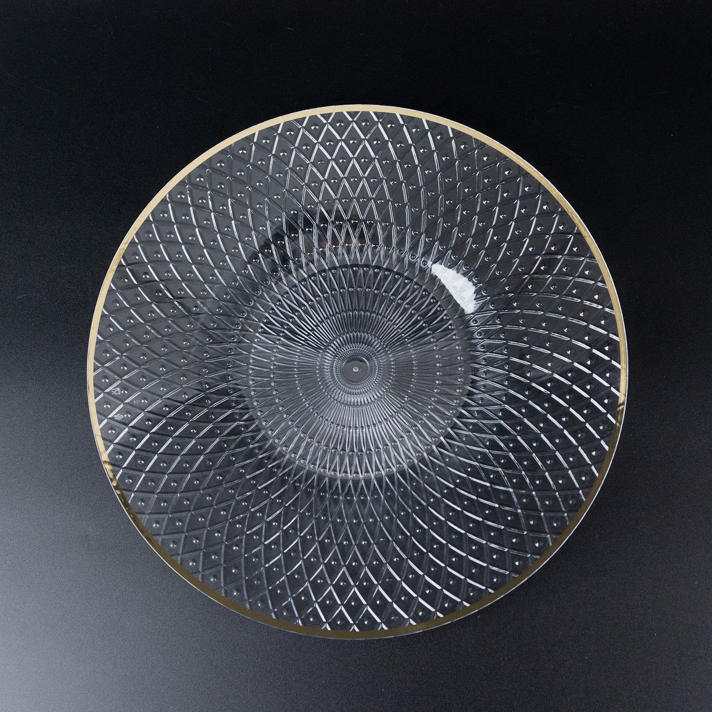 Clear plastic dinner plate with a radial diamond-cut pattern and gold rim.