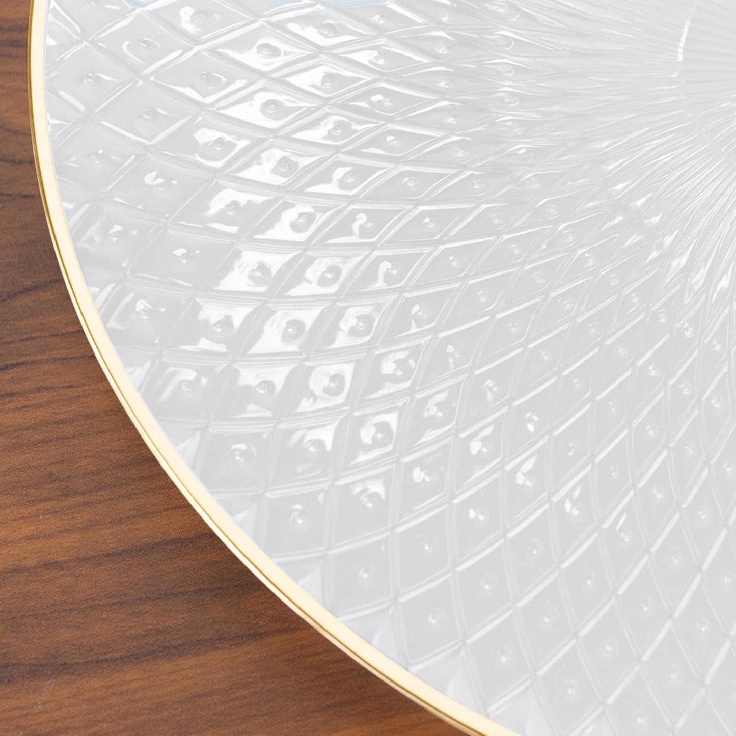 Round pearl white plastic dinner plate with gold rim and diamond-cut pattern.