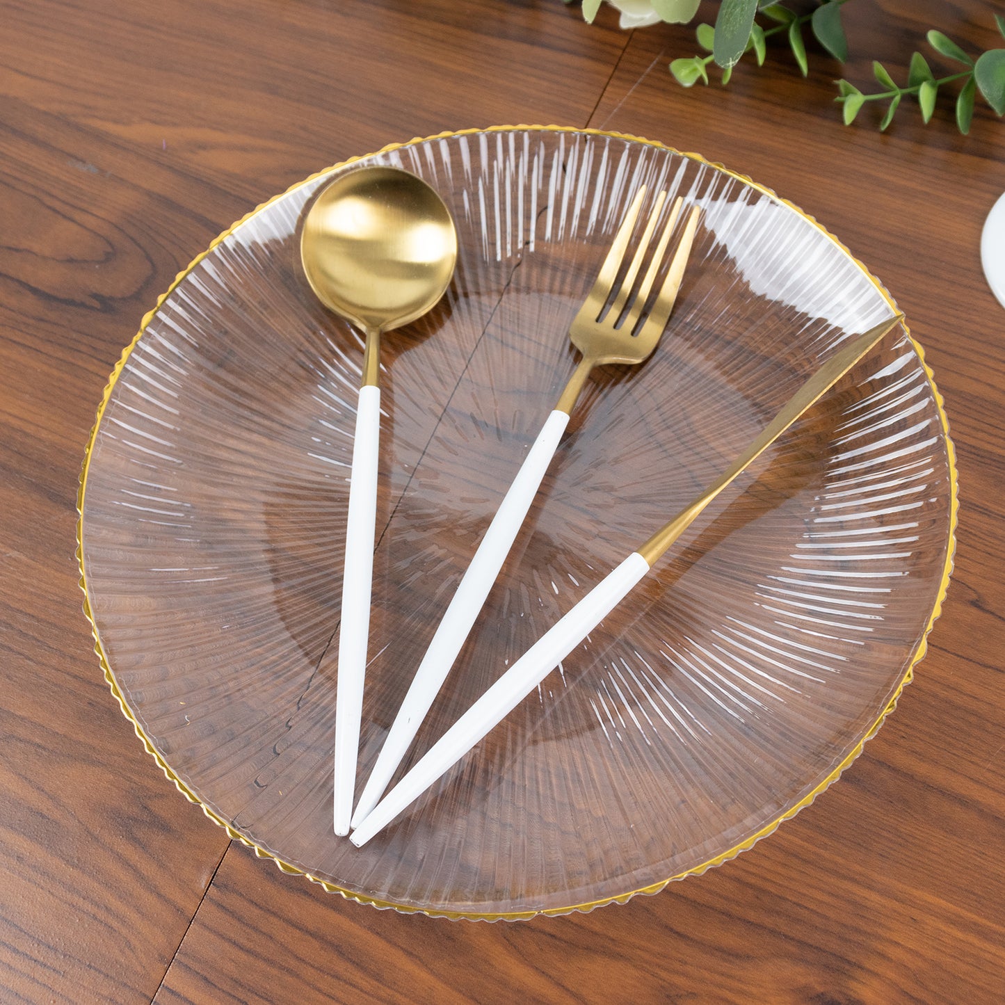 Clear plastic dinner plate with gold rim and ribbed sunburst pattern.