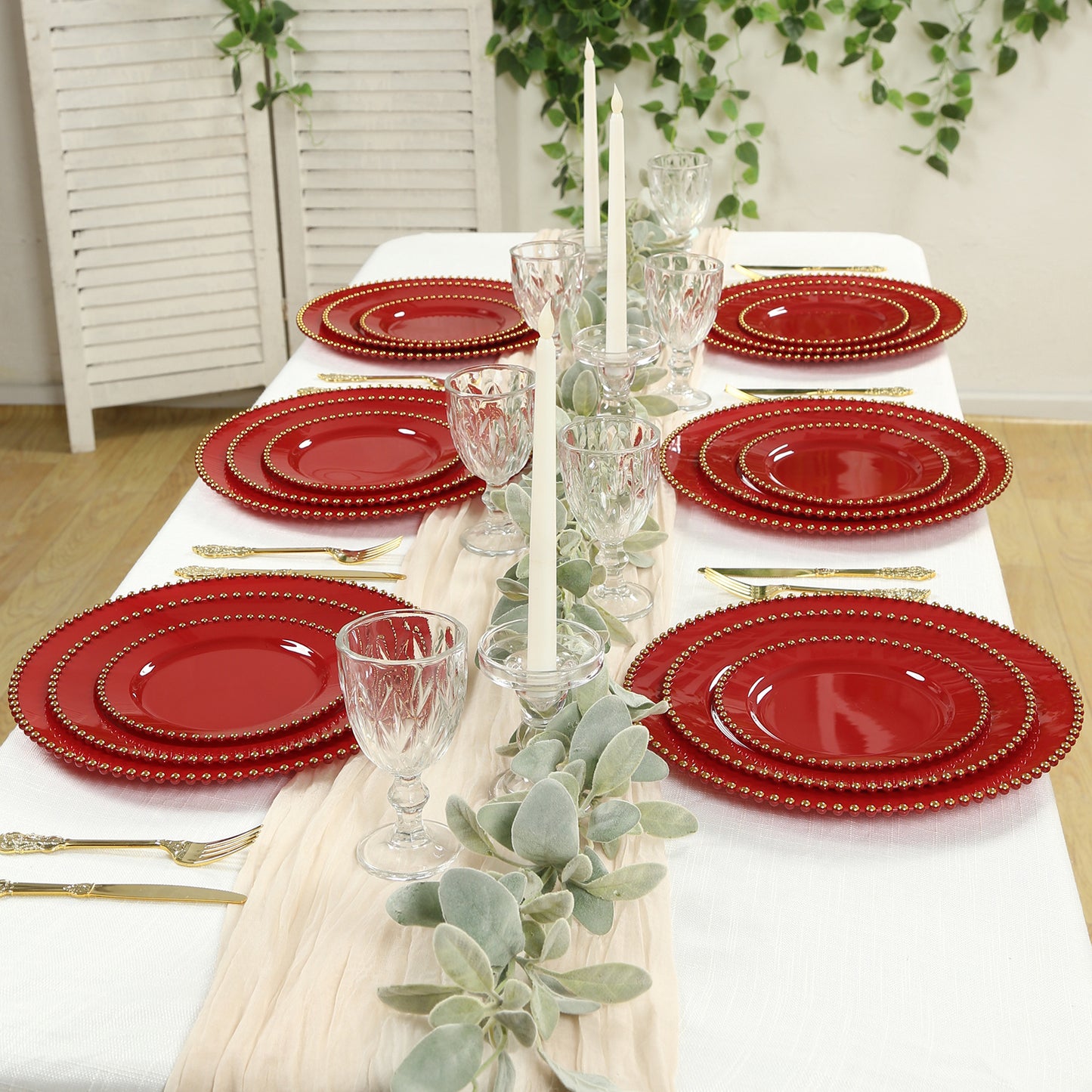 Red disposable dinner plates with gold beaded rim set for a festive table setting.