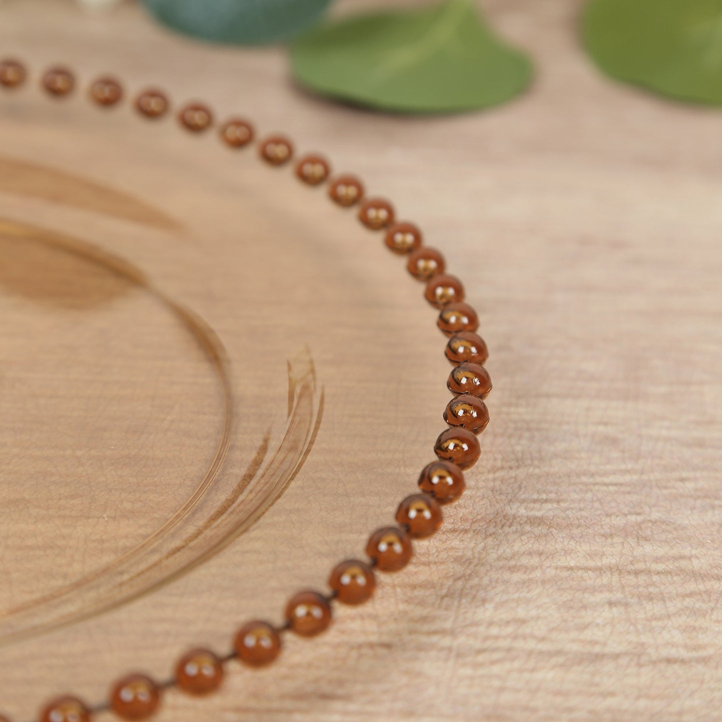 Amber gold beaded rim disposable dessert plate on a wooden surface.