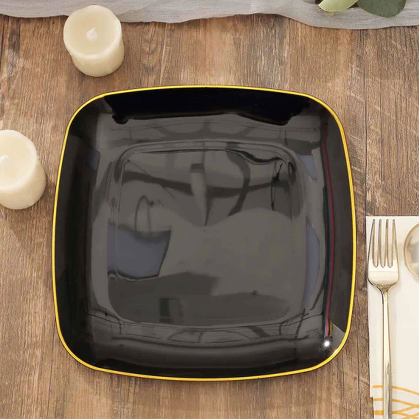 10" black with gold rim square plastic dinner plate on a wooden table.