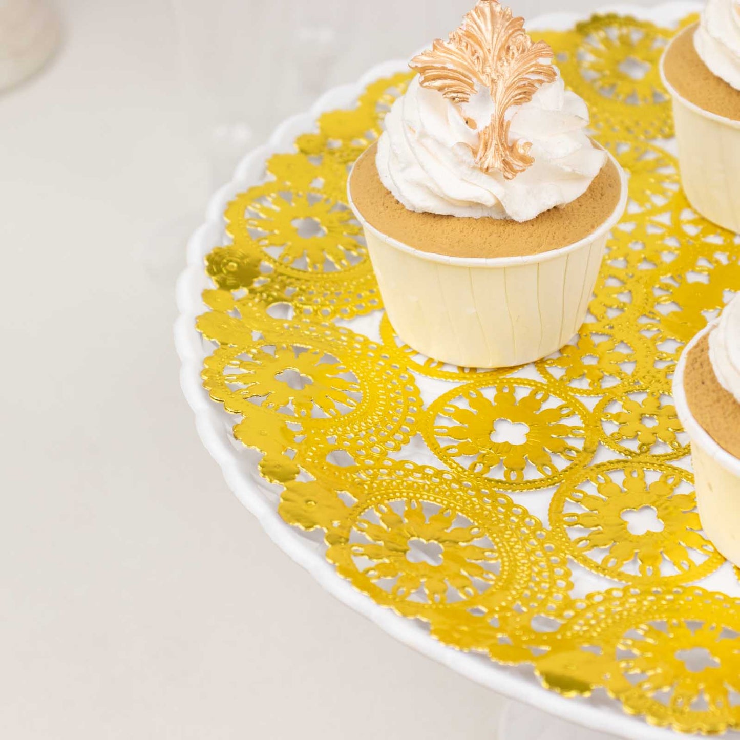 Metallic gold paper lace doilies on a cake stand with cupcakes.