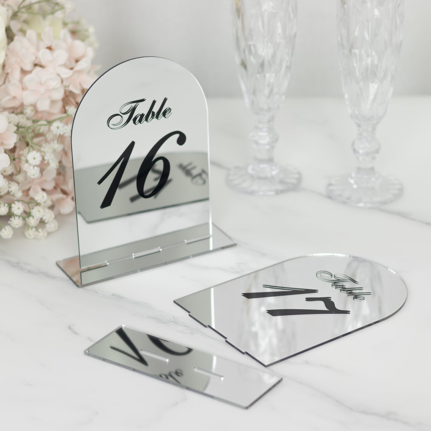 Silver mirror arch table numbers with black print for wedding reception.