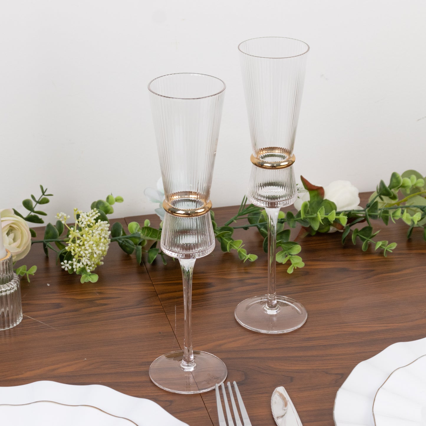 Clear champagne flutes with gold ring accents on a wooden table.