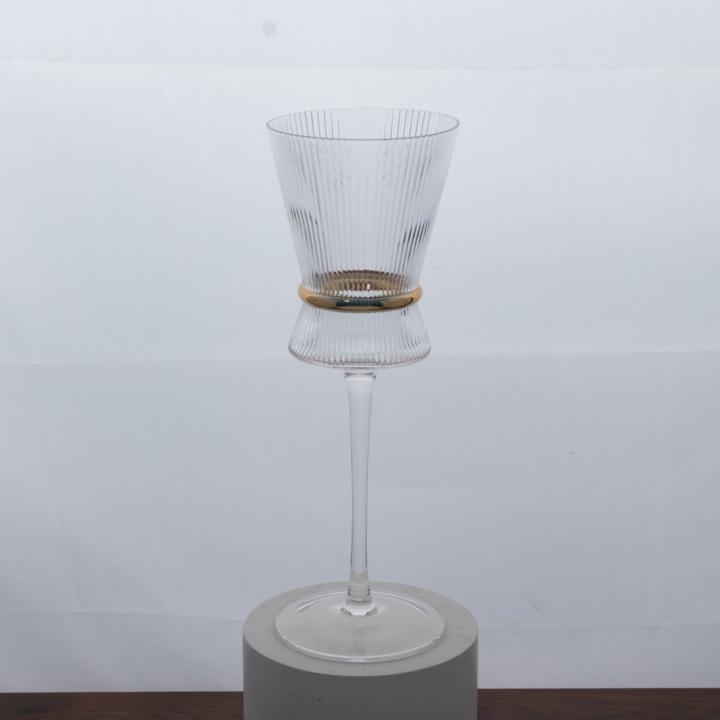 Clear wine glass with ribbed design and gold ring accent, elegant for celebrations.