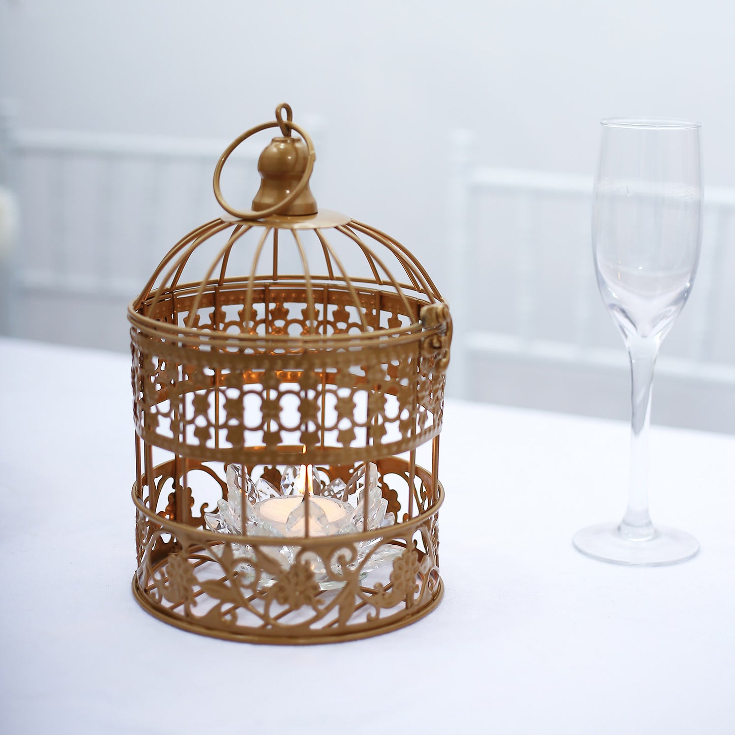 Metallic gold wrought iron bird cage card holder on a table.