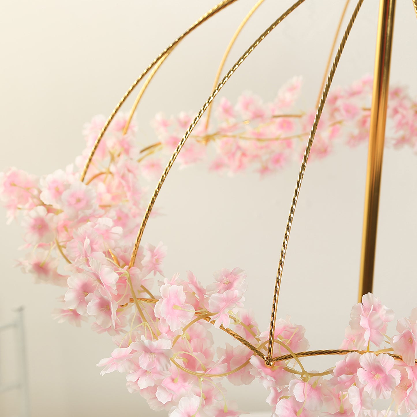 Gold metal umbrella flower stand with pink floral accents.