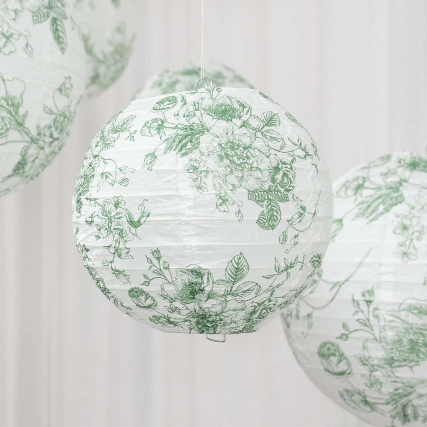 White and sage green floral paper lanterns hanging decoratively.