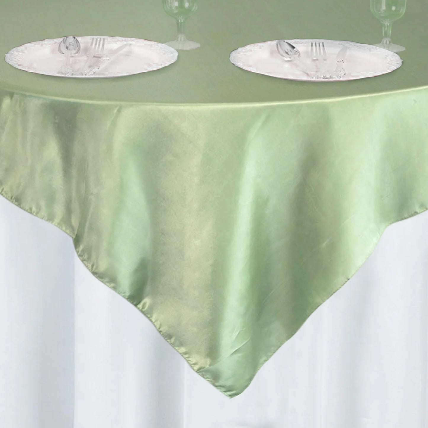 Sage green satin table overlay on a round table setting with plates.